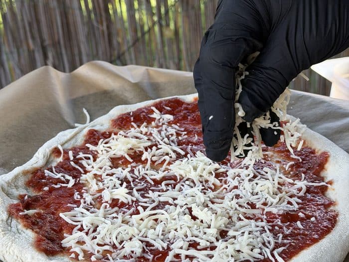 Käse wird auf die Pizza gestreut