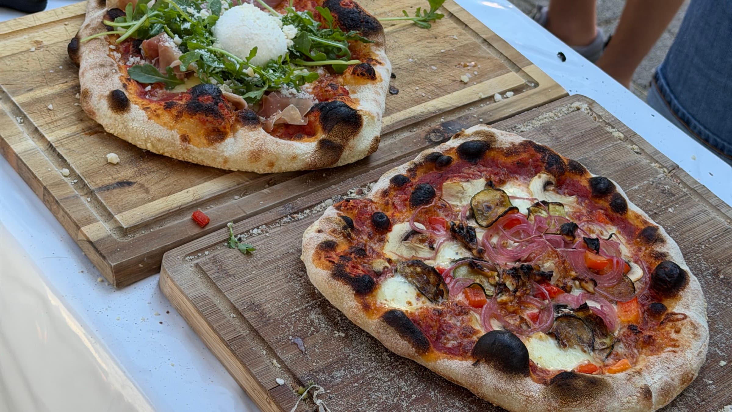Zwei frisch gebackene Pizzen auf Holzbrettern bei einem Outdoor-Event