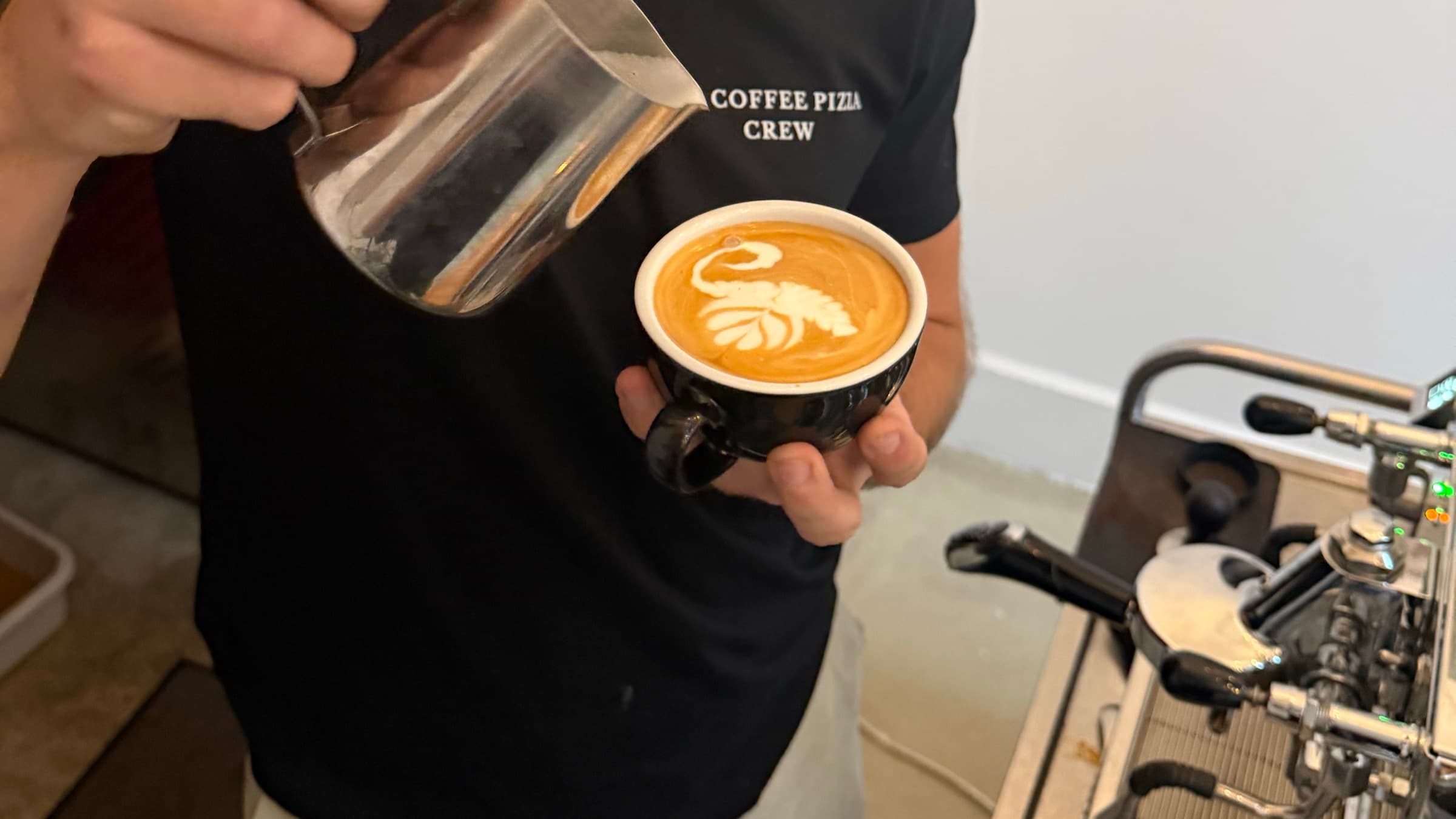 Barista von SIC Coffee Pizza gießt Latte Art neben der Siebträgermaschine