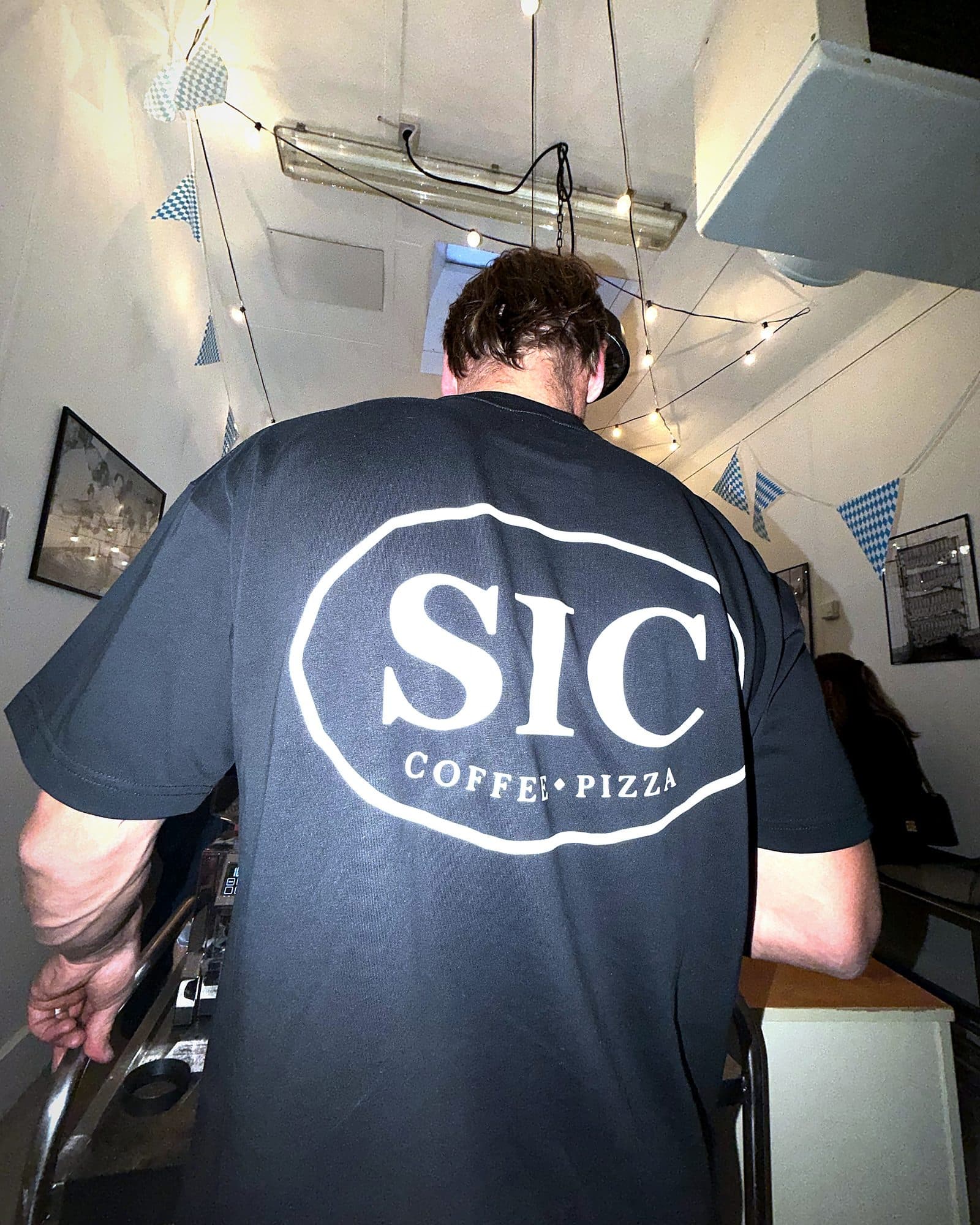 Barista von SIC Coffee Pizza an der Siebträgermaschine bei einem Pop-up-Event, SIC-Logo auf dem Rücken